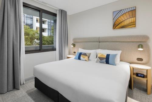 a bedroom with a large bed and a window at Quest at Sydney Olympic Park in Sydney