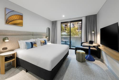 a hotel room with a bed and a flat screen tv at Quest at Sydney Olympic Park in Sydney
