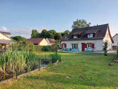 a white house with red doors and a yard at la picarde in Tours-en-Vimeu