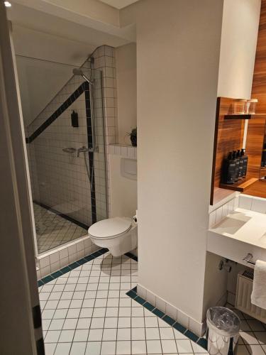 a bathroom with a shower and a toilet and a sink at Mercure Tagungs- & Landhotel Krefeld in Krefeld