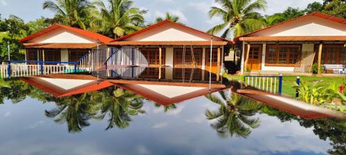 a house with its reflection in the water at De Orchid Resort in Agonda