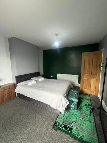 a bedroom with a bed and a green wall at Giga Residential 4 Bedrooms, 8 guests , Near City Centre, Arcade Machine, Sky TV, Netflix, Free Wifi, Free Parking in Newcastle upon Tyne