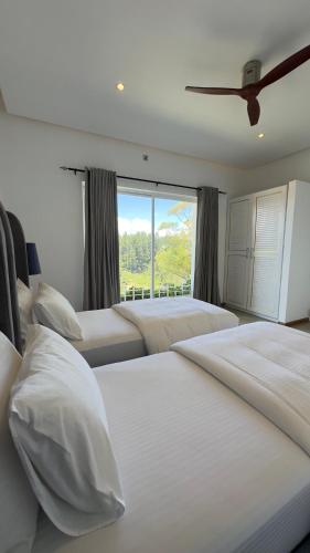 a bedroom with two beds and a large window at Benito Bungalow, Haputale by The Serendipity Collection in Haputale