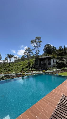 a large blue swimming pool with a house in the background at Benito Bungalow, Haputale by The Serendipity Collection in Haputale
