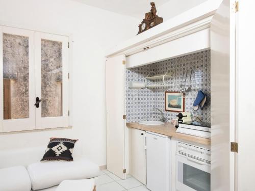 a kitchen with white cabinets and a white couch at La Dimora del Re in Erice