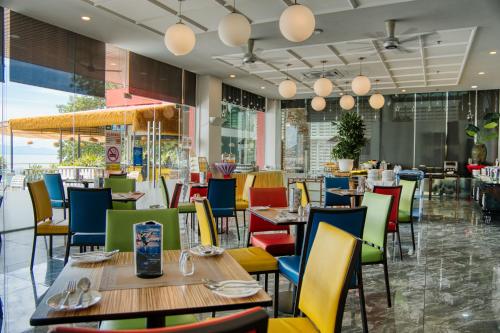 a restaurant with tables and chairs and windows at Hotel Sentral Seaview @ ​Beachfront in George Town