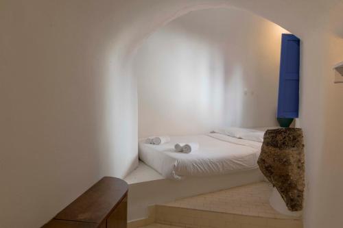 a bedroom with a white bed with a blue window at Gemini Cave Florina in Oia
