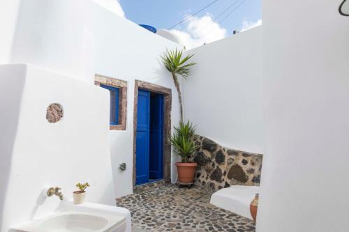 a bathroom with white walls and a blue door at Gemini Cave Florina in Oia