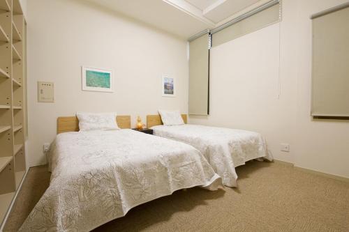 two beds in a room with white walls at 癒しの空間 One Earth in Akamine
