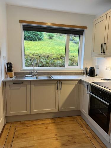a kitchen with a sink and a window at Brook Cottage in Portree