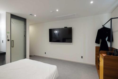a bedroom with a bed and a tv on the wall at Moor Hotel Mokpo By Aank in Mokpo