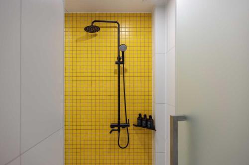 a bathroom with a shower with a yellow tile wall at Moor Hotel Mokpo By Aank in Mokpo