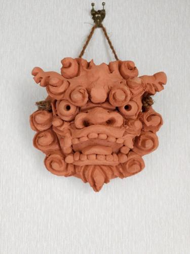 a wooden face ornament hanging on a wall at 癒しの空間 One Earth in Akamine