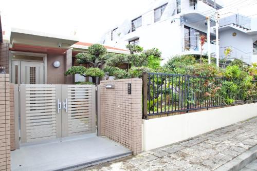 a fence with a gate in front of a house at 癒しの空間 One Earth in Akamine