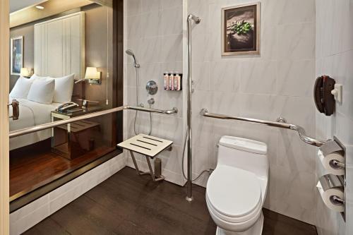 a bathroom with a toilet and a shower and a bed at Mövenpick Hotel Hanoi Centre in Hanoi