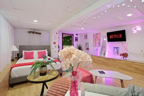 a living room with a bed and a table with flowers at Barbiecore Dream Pad in Sacramento in Sacramento