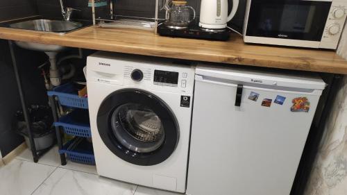 a kitchen with a washing machine under a counter at BURABAY apartments in Borovoye