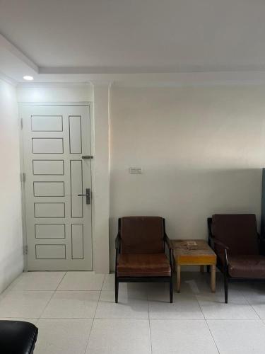 twee stoelen en een tafel in een kamer met een deur bij Giggsy Homestay at Belakang Balok in Bukittinggi