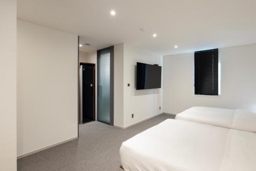 a bedroom with a white bed and a flat screen tv at Moor Hotel Mokpo By Aank in Mokpo