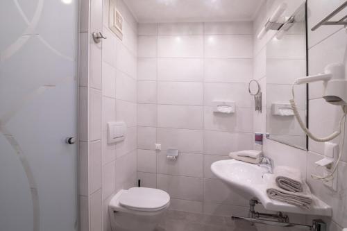 a white bathroom with a toilet and a sink at Ferienwohnungen Gabriel in Keutschach am See