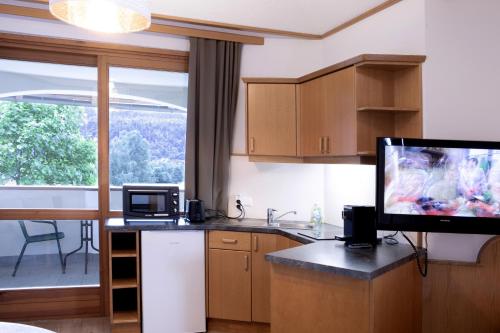 a kitchen with a tv on a counter and a kitchen with a table at Ferienwohnungen Gabriel in Keutschach am See