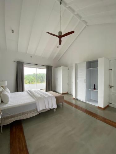 a white bedroom with a large bed and a ceiling fan at Benito Bungalow, Haputale by The Serendipity Collection in Haputale
