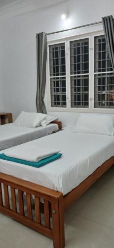 two beds in a room with two windows at annies inn homestay in Cochin