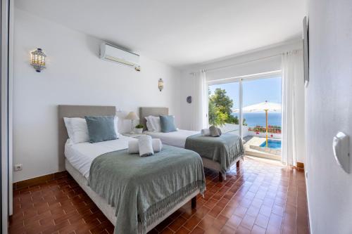 een slaapkamer met 2 bedden en uitzicht op de oceaan bij Casa Maresia da Salema in Salema