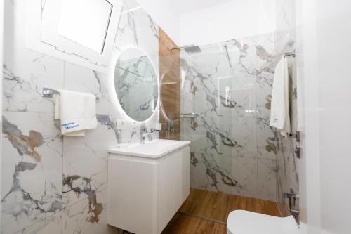 biała łazienka z umywalką i lustrem w obiekcie Lungomare Apartments we Wlorze