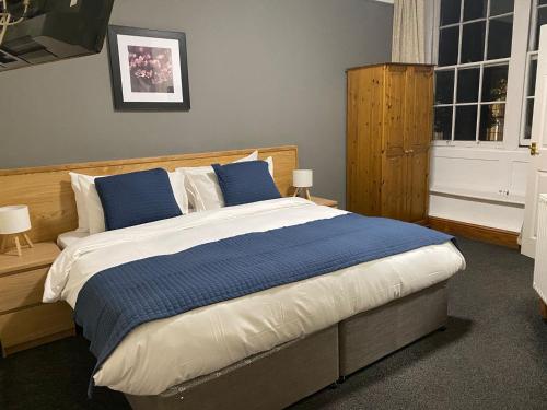 a bedroom with a large bed with blue pillows at Blue Boar in Frome