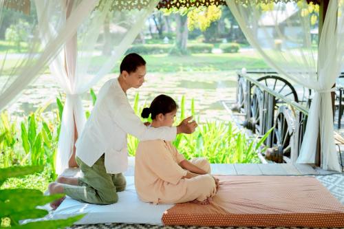 a man and woman sitting on a mattress under a tent at Lampang River Lodge in Lampang