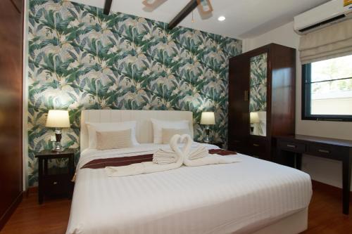 a bedroom with a large white bed with a floral wallpaper at Baan Ping Tara Tropical Pool Villa and Scooter in Ban Khlong Son