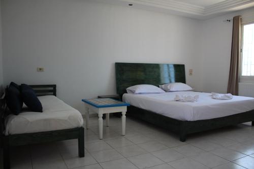 a bedroom with two beds and a table in it at Hôtel Medina in Sousse