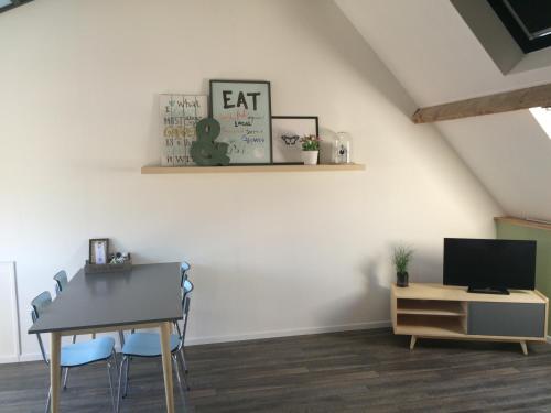 a dining room with a table and a tv at De Weegbrug in IJzendijke