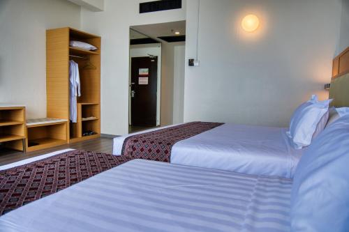 a hotel room with two beds and a closet at Hotel Sentral Seaview @ ​Beachfront in George Town