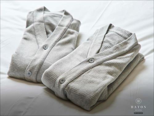 a pair of white sweaters sitting on a bed at BATON SUITE Okinawa-kourijima in Nakijin