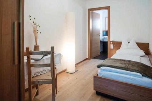 a bedroom with a bed and a chair in it at Farmhotel Moosmair in Campo Tures
