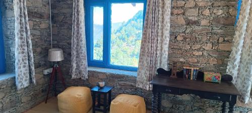 ein Wohnzimmer mit einer Steinmauer und einem Fenster in der Unterkunft Burans Kot Heritage Home - Ramgarh in Rāmgarh
