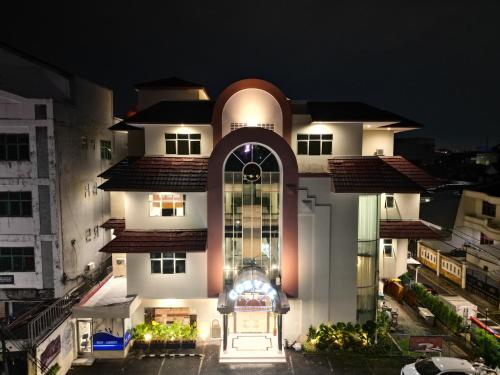 a large white building with a lit up facade at night at Corvel by Behomy in Jakarta