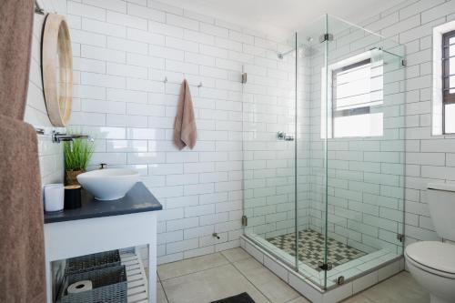 a bathroom with a shower with a sink and a toilet at Picnic Rock Seaside Accommodation in Keurboomstrand