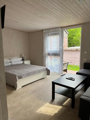 a bedroom with a bed and a table and a window at Vila KOPA Šventoji in Šventoji