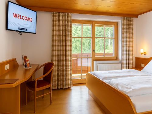 a hotel room with a bed and a desk and a television at GarniHotel zur Linde - Bayerischer Wald - aktivCard mit 154 kostenfreien Leistungen - kostenloser Parkplatz in Lohberg