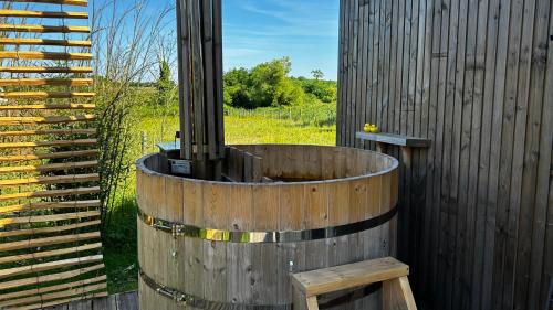 un tonneau en bois assis à côté d'une clôture dans l'établissement Ecolodge premium avec bain nordique, à Vallet