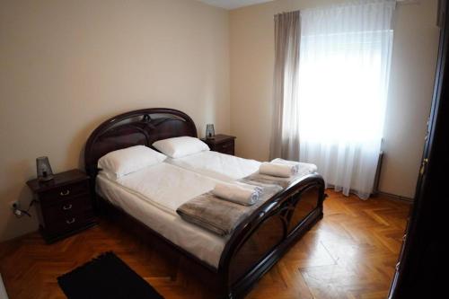 Un dormitorio con una cama con sábanas blancas y una ventana. en Apartmani Kula - Lux Apartman, en Novi Banovci