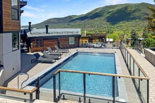 a swimming pool with chairs and a house at Shadow Mountain 10 in Aspen