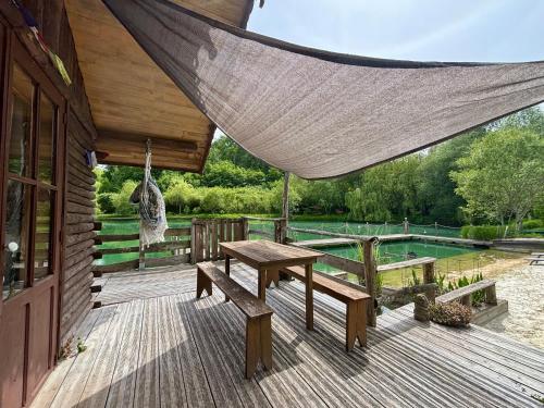 une terrasse en bois avec une table de pique-nique et des bancs dans l'établissement La cabane sur le lac aux Temps des Sources, à Veyrines-de-Domme