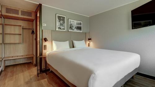 une chambre avec un grand lit blanc dans une pièce dans l'établissement Campanile NATURE - Cergy Pontoise, à Pontoise