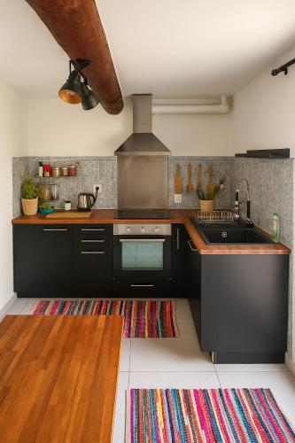 - une cuisine avec des placards noirs, un évier et un tapis dans l'établissement Maison au cœur de La Couronne Mer et commerces à pied, à Martigues