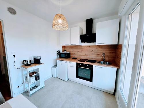 une cuisine avec des armoires blanches et un évier dans l'établissement Bourneil - Séjour à Auxerre, à Auxerre