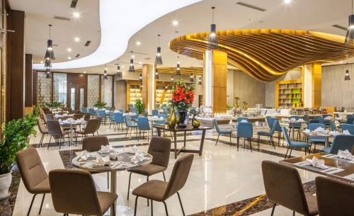 a restaurant with tables and chairs and a large ceiling at Muong Thanh Luxury Nhat Le Hotel in Dong Hoi